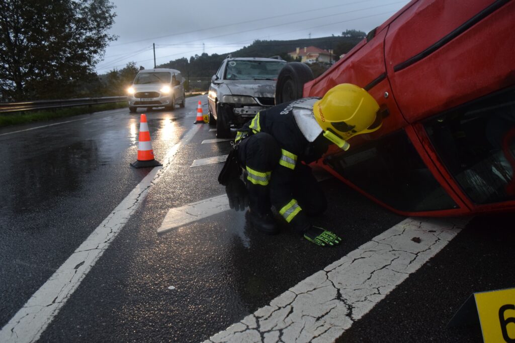 Firefighter attending to an overturned car on a rainy road in Póvoa de Lanhoso, Braga, Portugal.